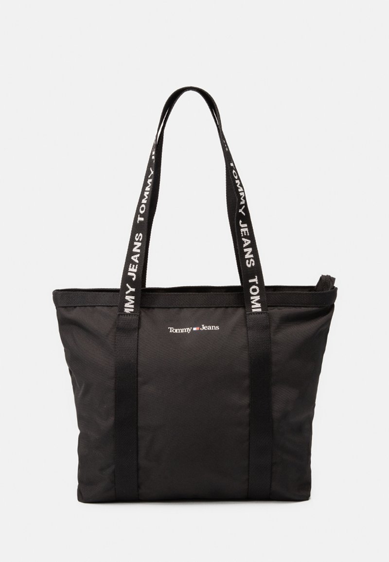 Sac fourre-tout noir en tissu durable, avec des poignées noires doubles et un logo de marque blanc accompagné de texte signature imprimé le long des sangles.