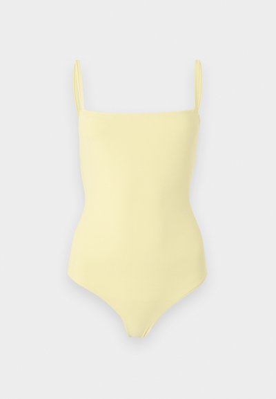 Απαλό κίτρινο ολόσωμο μαγιό με λεπτές τιράντες και ίσια γραμμή στο ντεκολτέ, παρουσιασμένο σε απλό φόντο.
