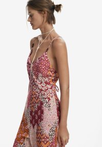 Vestido maxi con patrones florales y geométricos multicolores, tirantes de espagueti ajustables y detalle de lazo en la parte posterior.