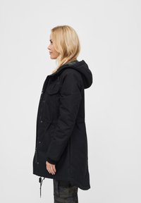 Czarna parka z kapturem, zapinana na zamek błyskawiczny i zatrzaski, z dwoma kieszeniami na piersi oraz elastycznym ściągaczem w talii.