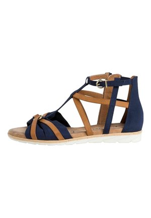 Flad sandal med marineblå og tan remme, ankelspænde, polstret fodseng og hvid tekstureret sål.
