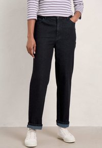 Černé džíny se straight fit, ohrnutými manžetami a předními kapsami, zkombinované s pruhovaným topem s dlouhým rukávem a bílými teniskami.