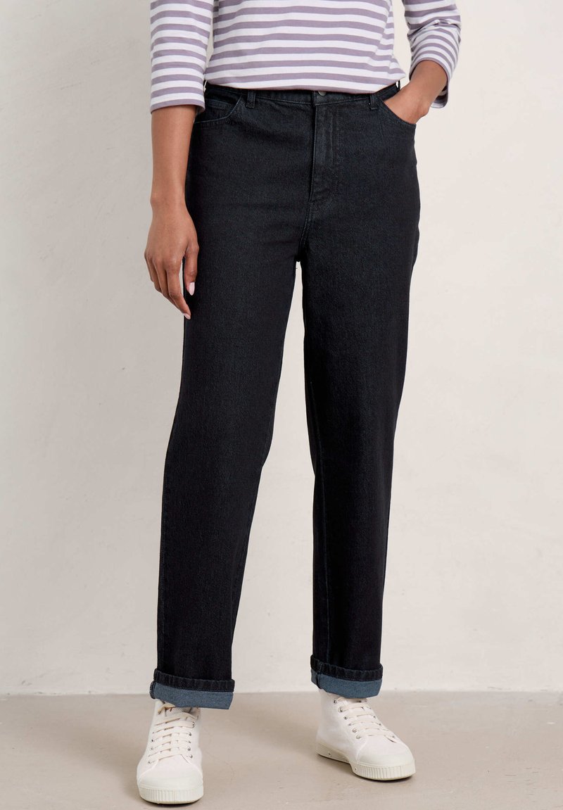 Černé džíny se straight fit, ohrnutými manžetami a předními kapsami, zkombinované s pruhovaným topem s dlouhým rukávem a bílými teniskami.