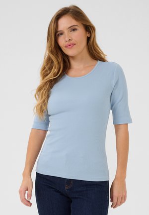 Light blue, ribbed short-sleeve top with a round neckline, smooth texture, and a fitted silhouette. Paired with dark denim.