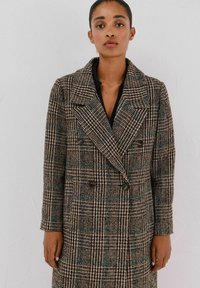 Dubbelzijdige jas in een houndstooth-patroon met een combinatie van bruin en teal kleuren, van gestructureerde wol stof, met grote revers en vier zwarte knopen.