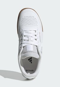 Scarpa da ginnastica bianca con tomaia in mesh, dettagli perforati, lacci piatti e suola in gomma. Presenta il marchio dell'inserto Ortholite.