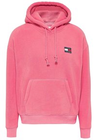 Rosa Fleece-Kapuzenpullover mit Fronttasche, Kordelzugkapuze und einem rechteckigen Logo-Patch mit der Aufschrift "TOMMY JEANS" in Schwarz und Weiß.