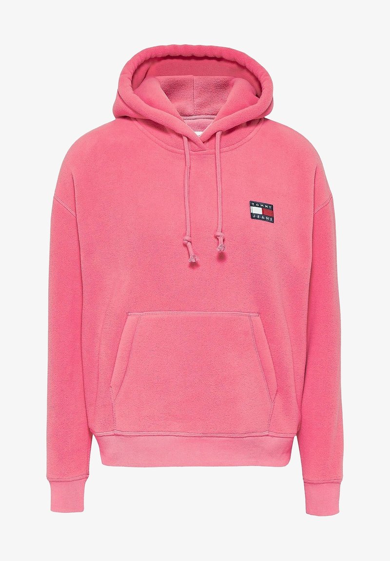Rosa Fleece-Kapuzenpullover mit Fronttasche, Kordelzugkapuze und einem rechteckigen Logo-Patch mit der Aufschrift "TOMMY JEANS" in Schwarz und Weiß.