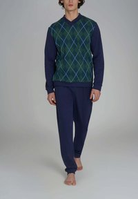Maglione argyle verde e blu navy con maniche lunghe, abbinato a pantaloni della tuta blu navy. Il tessuto sembra morbido, con una vestibilità rilassata e polsini a coste.
