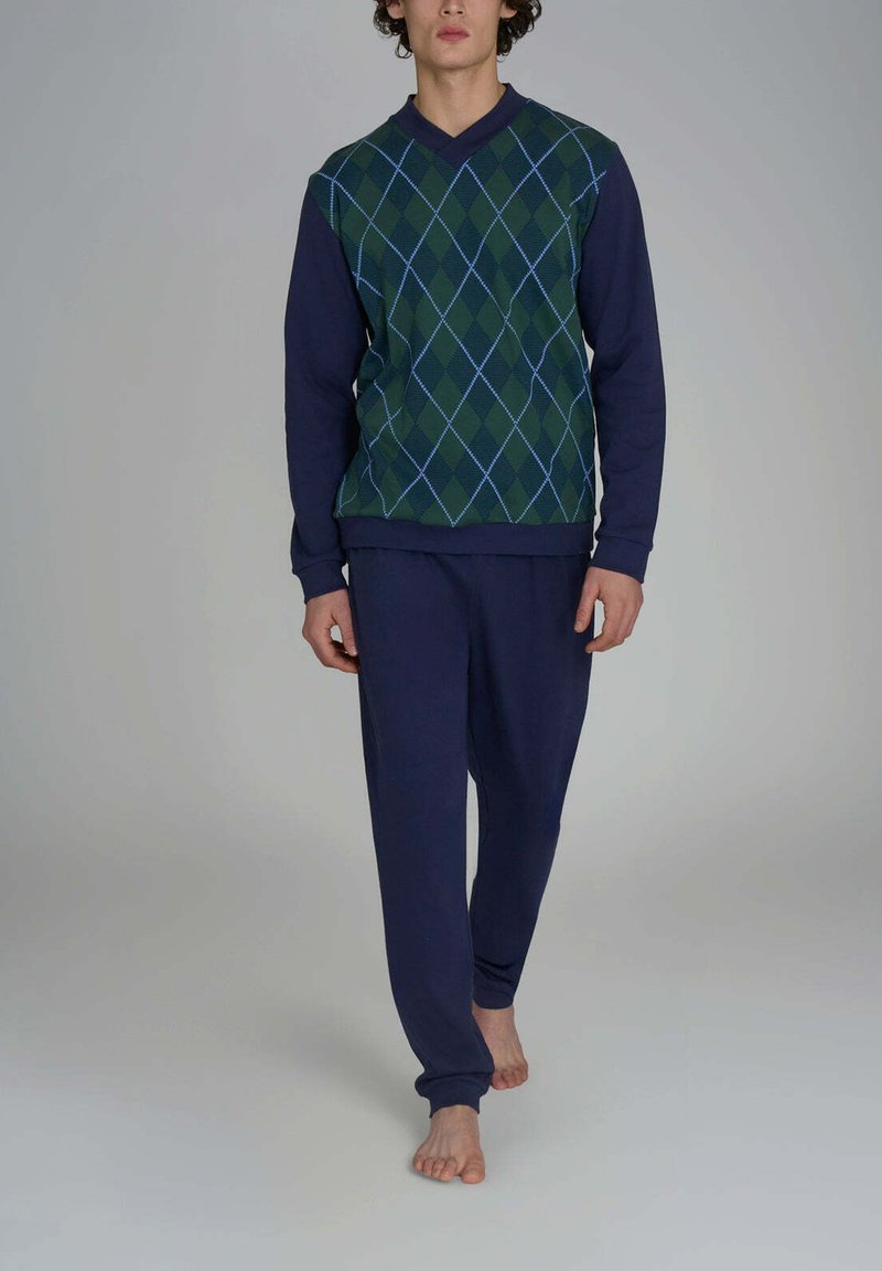 Maglione argyle verde e blu navy con maniche lunghe, abbinato a pantaloni della tuta blu navy. Il tessuto sembra morbido, con una vestibilità rilassata e polsini a coste.
