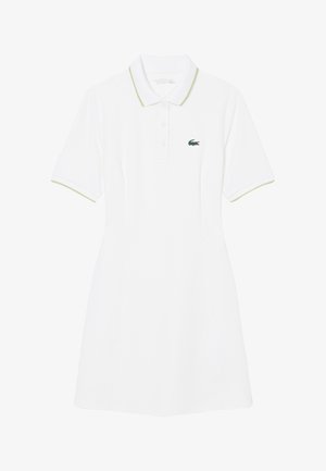 Vestido tipo polo blanco de manga corta con ribete verde en el cuello y las mangas, tapeta de botones en la parte delantera y un pequeño logo de cocodrilo bordado en verde.