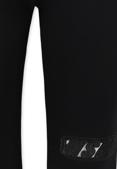Leggings neri realizzati in materiale elastico, con un'etichetta logo in tessuto nero sulla parte bassa della gamba. Tessuto liscio con un design aderente.