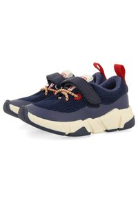 Zapatillas deportivas de malla en color marino con acentos en blanco y rojo, con una correa de gancho y bucle y una suela de goma texturizada. Los cordones son multicolores.
