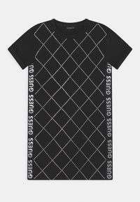 Czarna sukienka t-shirtowa z diamentowym wzorem utworzonym przez przezroczyste cyrkonie, z logo "GUESS" nadrukowanym po bokach na biało.