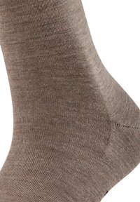 Calzino marrone realizzato in materiale morbido e strutturato, con un design a coste, cuciture uniformi e punta senza cuciture per il massimo comfort.