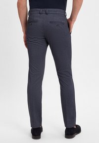 Marineblaue Anzughose mit strukturiertem Muster, slim-fit Design, Five-Pocket-Stil und dezenten Akzenten, ausgestattet mit rückseitigen Knopfverschlüssen.