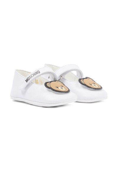 Chaussures pour bébé blanches avec fermetures à bride, ornées de têtes d'ourson marron sur les orteils et du texte "MOSCHINO" sur les brides.