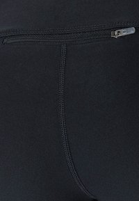 Sorte strækstof leggings med en sidelomme med lynlås og forstærket syning, der giver en tætsiddende og glat tekstur.
