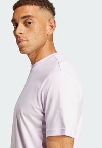 Světle fialové tričko s kulatým výstřihem, krátkými rukávy a měkkou texturou. Boční pohled zdůrazňuje střih a detaily šití.