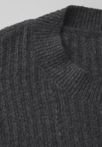 Dunkelgrauer, gerippter Strickpullover mit rundem Ausschnitt und weicher Textur, der ein gemütliches und geschichtetes Design präsentiert.