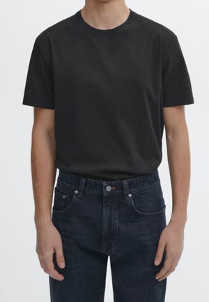 Black short-sleeve t-shirt made of soft cotton, featuring a round neckline. Paired with dark blue denim jeans, showcasing a classic cut and pockets.