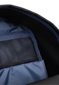 Černý interiér tašky s modrou textilní podšívkou, uzavřenou kapsou na zip a síťovanou přihrádkou, zdůrazňující strukturu a organizaci.