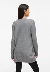 Gray knitted sweater with long sleeves, ribbed hem, and side slits. Soft texture and relaxed fit, suitable for layering.