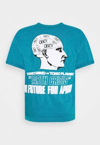 Turkos t-shirt med svart och vit hjärngrafik märkt "OBEY" och texten "Toxiskt sinne = Toxisk planet 'Jordkris' Ingen framtid för aphi".