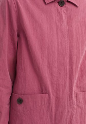 Veste courte rose en tissu léger, dotée d'un col, de deux poches avant avec des boutons marron, et d'une finition texturée.