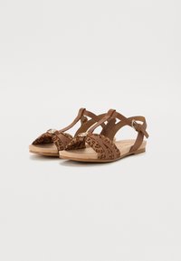 Brown strappy sandals featuring a leopard print pattern, flat sole, and decorative buckle accents on the straps. Textured upper material.
