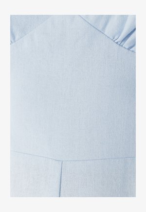 Lyseblåt tekstureret stof med subtile søm linjer og plisserede detaljer langs kanten, som viser nærbillede af beklædningskonstruktion.