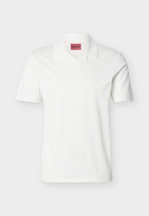 Hvit kortermet poloshirt med oppbrettet krage og rød HUGO-merkelapp på innsiden av halsen.