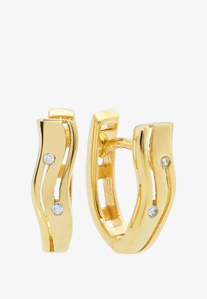 Boucles d'oreilles créoles en ton or avec un design ondulé, ornées de deux petites pierres claires serties de manière asymétrique à l'avant. Finition lisse et polie.