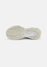 Shoe sole featuring a white and light beige rubber material with multi-directional treads and grooves for traction and support.