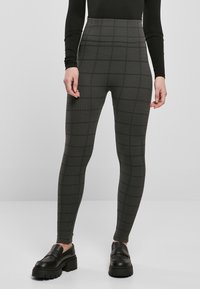 High-waisted leggings in a dark grey plaid pattern, featuring a stretchy fabric and a slim fit, paired with chunky black slip-on shoes.
