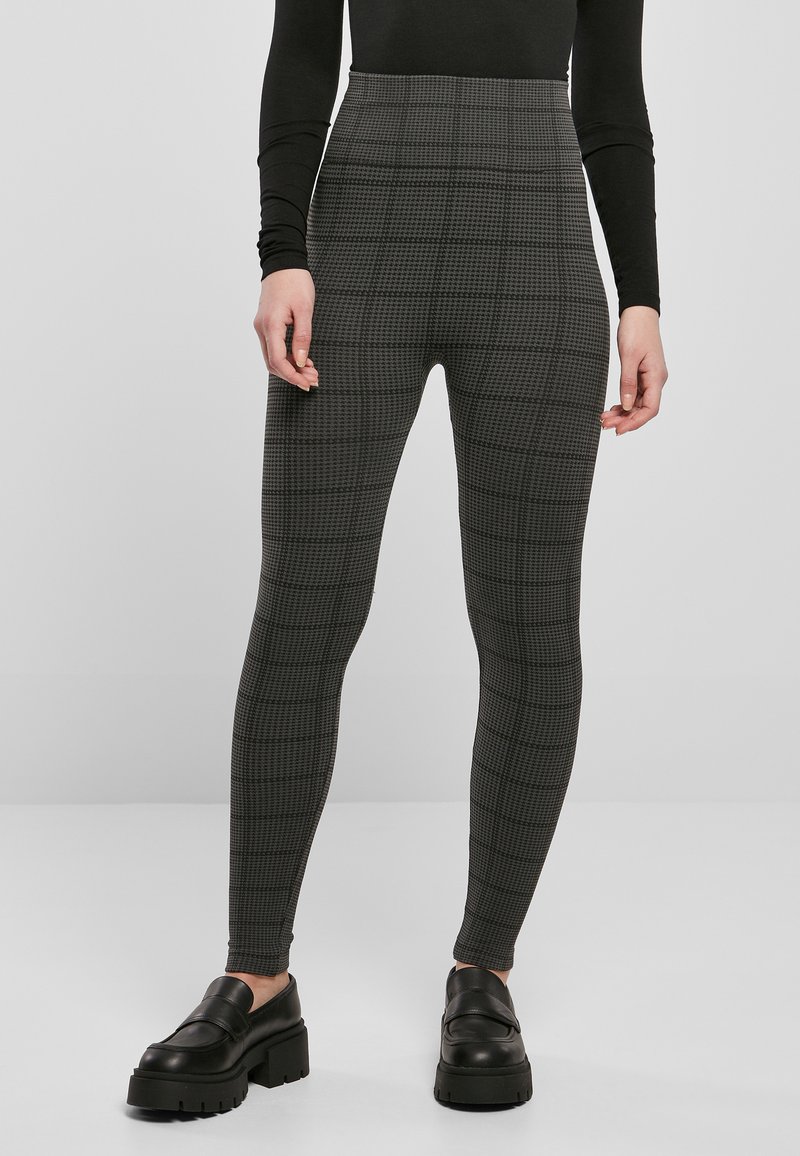 High-waisted leggings in a dark grey plaid pattern, featuring a stretchy fabric and a slim fit, paired with chunky black slip-on shoes.