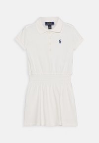 Valkoinen lyhythihainen polo-mekko, jossa on kaulus, nappilista, joustava vyötärö ja pieni tummansininen brodeerattu logo rinnassa.