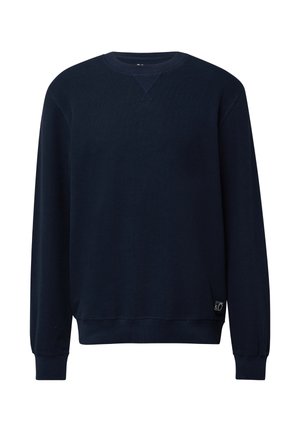 Sudadera azul marino con mangas largas, cuello redondo acanalado y puños. Presenta un pequeño parche de logo en el lado inferior izquierdo. Textura suave.