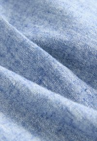 Světle modrá látka s texturovaným tkaním, s jemnými variacemi barev a měkkým, hladkým povrchem.