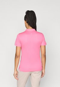 Polo majica v svetlo roza barvi z teksturiranim vzorcem, kratkimi rokavi in klasičnim ovratnikom. Stranski razporki na robu za lažje gibanje.