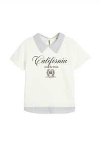 Camisa blanca de manga corta con cuello y dobladillo a rayas. Presenta el texto "California Living the Dream" y un emblema decorativo en negro.