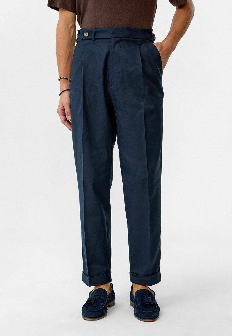 Marineblauwe high-waisted broek met plooien, voorzien van zijzakken en verstelbare taillebanden. Glad stoffen met een getailleerde pasvorm.