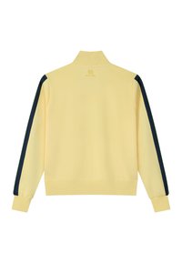 Chaqueta de manga larga en amarillo pálido con rayas negras a lo largo de cada manga, puños y dobladillo acanalados, y un cuello alto acanalado tipo mock neck.