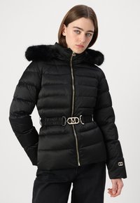 Black puffer jacket with a faux fur hood, horizontal quilted design, silver hardware, and a cinched waist with a decorative belt accent.