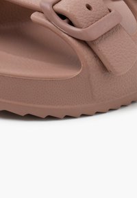 Infradito in gomma marrone con superficie testurizzata, dotate di una fascia larga e una fibbia regolabile, progettate con una soletta sagomata per il massimo comfort.