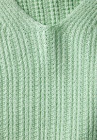Tessuto lavorato a maglia verde chiaro con un motivo a righe verticali. Il materiale appare morbido e peloso, mostrando un design accogliente e dettagliato.