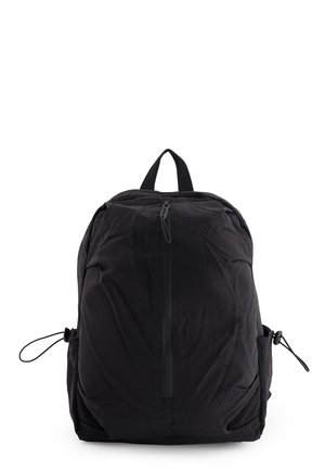 Black nylon backpack with central zipper, adjustable side pockets, and top carry handle, standing upright on a white background.