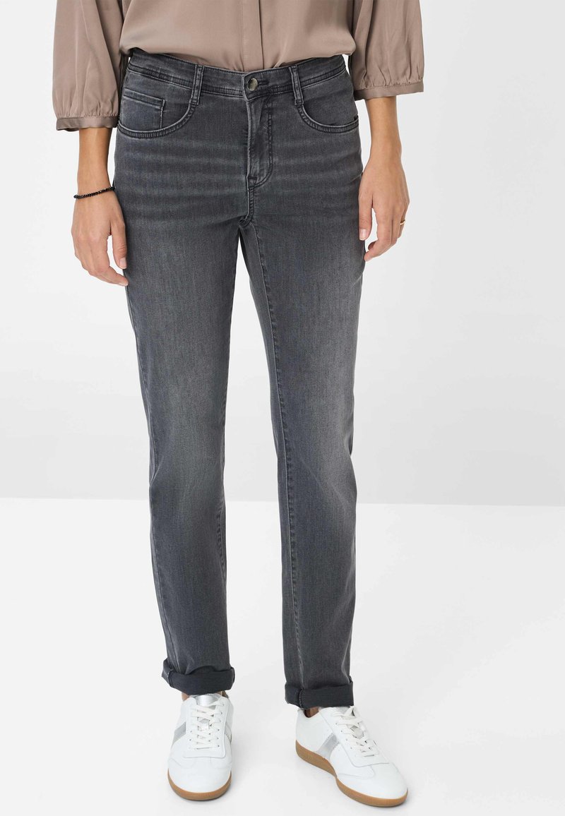 Grå denim jeans med lige pasform, der har subtilt slid, fem lommer og op卷ede nederste kanter, parret med hvide sneakers.