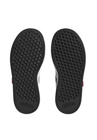 Suola di scarpa nera in gomma con trama a nido d'ape. Presenta il marchio "adidas" in rilievo e dettagli rossi sul lato.