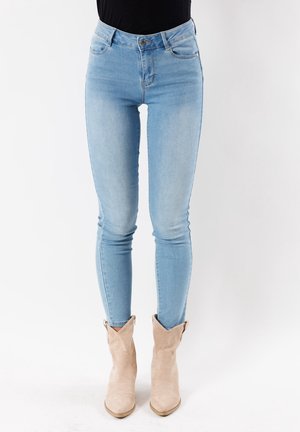 Jean skinny bleu clair en denim, avec une taille haute, des poches avant et un effet délavé. Assorti à des bottines en suède beige.